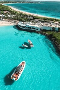 Stunning aerial view of motorboats on turquoise waters near a coastal resort.